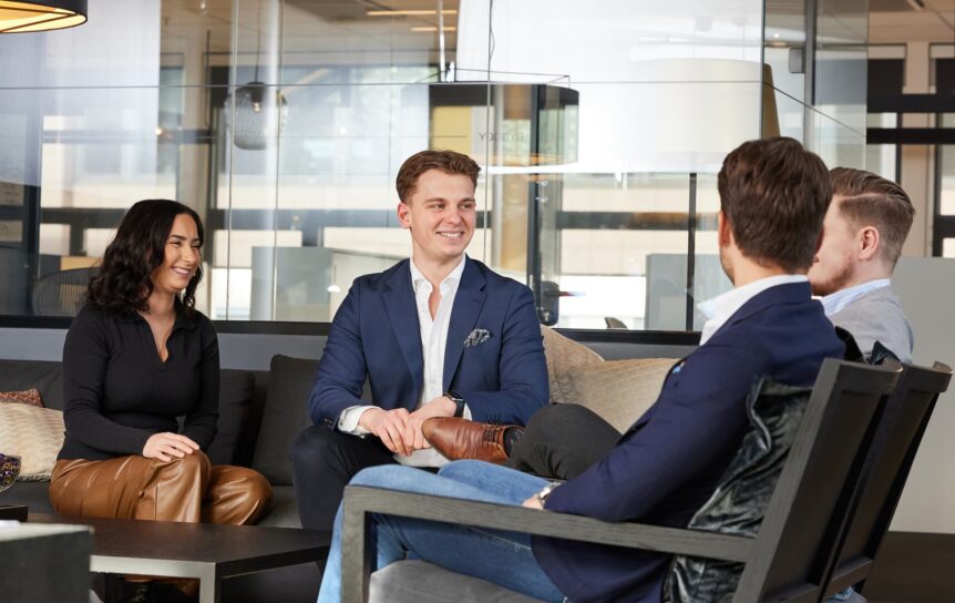 Fire personer sitter og snakker sammen på kontoret.