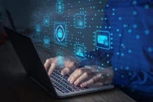 Bilde av to hender som skriver på en laptop.