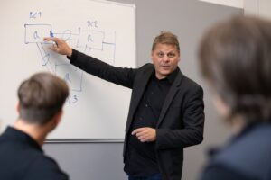 Man pekar på en tavla med en blå tusch.