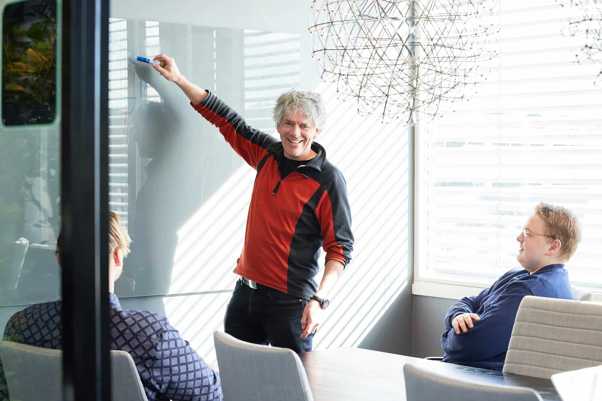 Tre män i ett mötesrum.