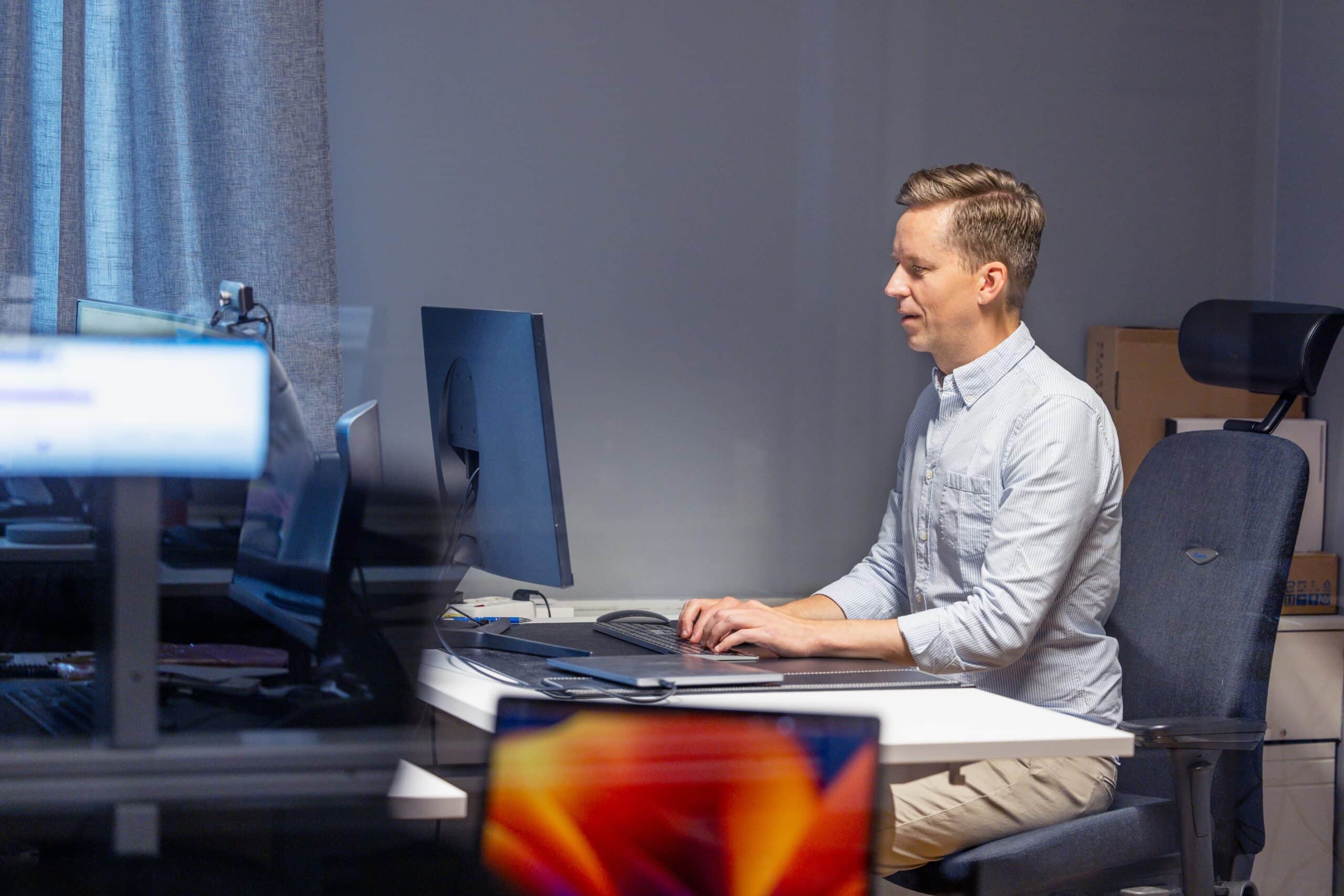 Man sitter framför skärm på kontor.