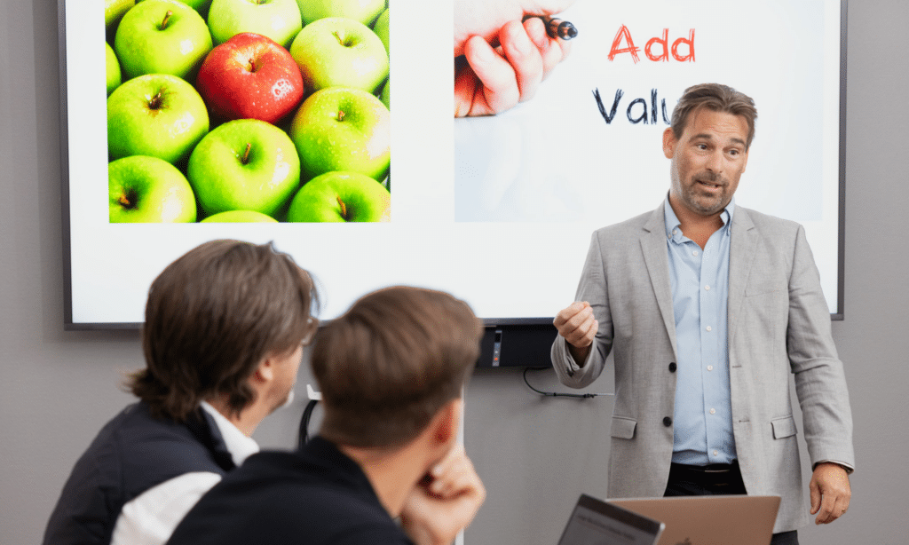 Mann holder foredrag foran en skjerm.