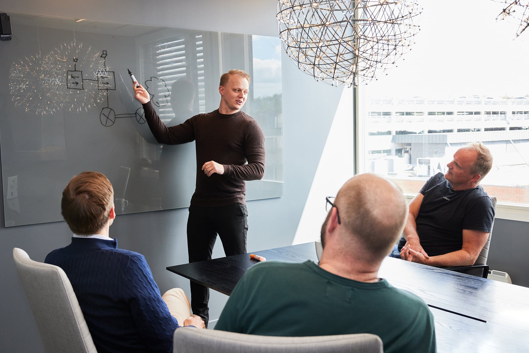 Mann tegner på tavle og forteller.