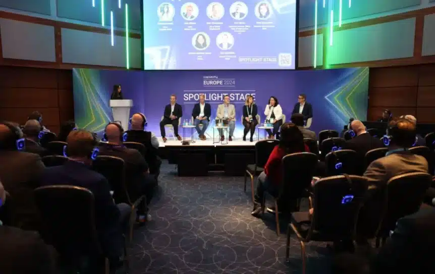 Seks mennesker på en scene under en konferanse.