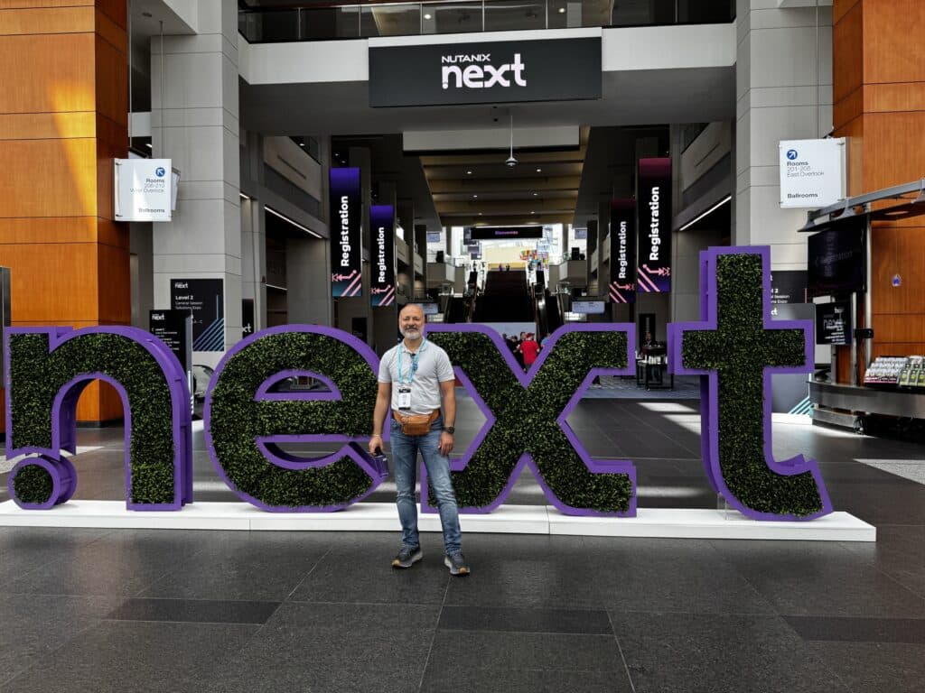 Mann med skjegg foran Nutanix Next-skilt.