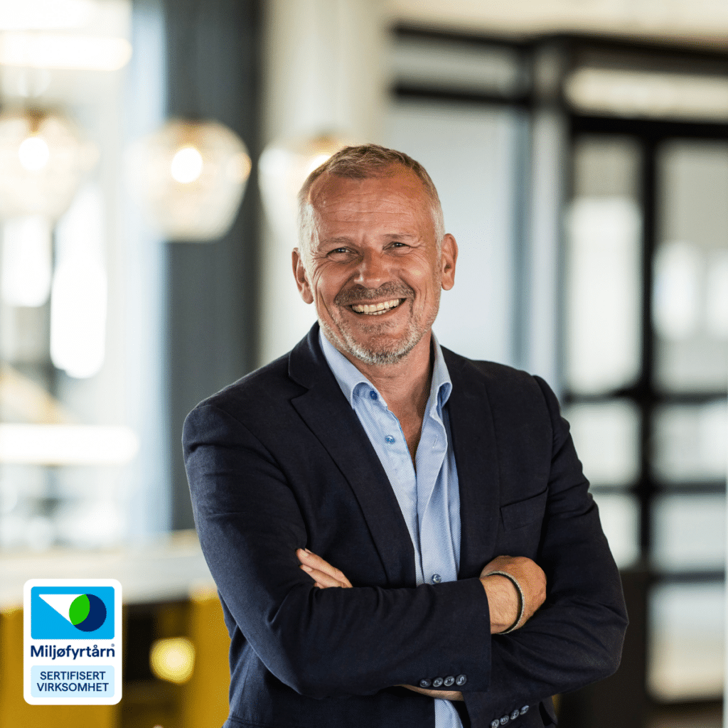 Smilende mann i dress ved siden av Miljøfyrtårn-logo.